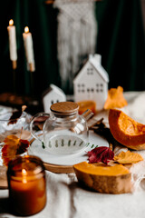 Empty glass teapot ready for brewing pumpkin tea surrounded by autumn candles, leaves and warm home decor.