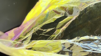 Closeup of wrinkled holographic foil with vibrant yellow, pink and purple reflections. Abstract iridescent texture with shiny surface - Powered by Adobe