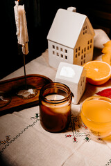 Autumn candlelight scene with black glass candle, hot tea, and dry leaves on cozy table. Fall still life concept.