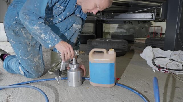 Man in garage adds natural and non toxic lanolin based rustproofing product to spray gun for car under body treatment.