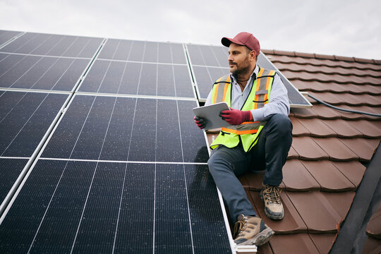 Male engineer using digital tablet during inspection of solar rooftop.