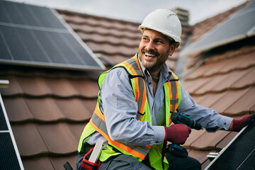 Happy worker mounting solar system on roof of residential building. © Drazen