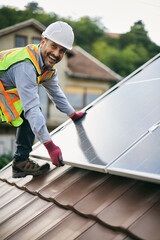 Happy solar panel engineer working on rooftop and looking at camera.