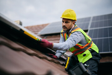 Male engineer during solar panels maintenance on roof of house. © Drazen
