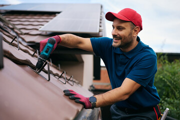 Happy repairman fixing tiles on roof of house.