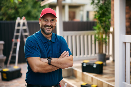 Confident home repairman standing with crossed arms and looking at camera