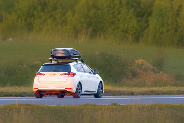 SUV with Roof Box Driving Along Green Fields
