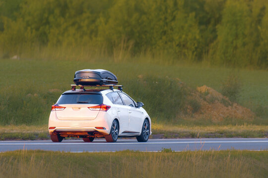 SUV with Roof Box Driving Along Green Fields