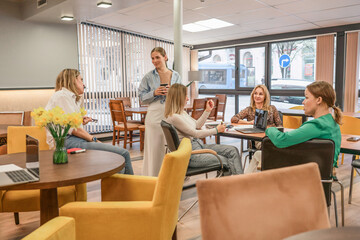 Meeting Businesswomen Laptops: Group discusses work, daytime, in modern office space near window.