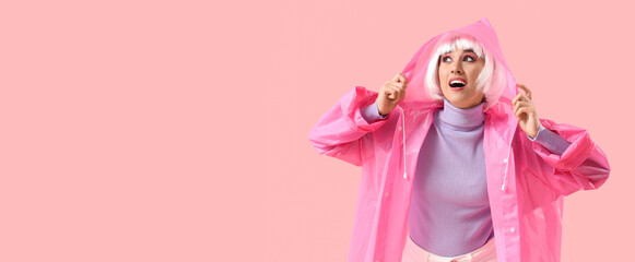 Beautiful young happy woman in white wig and raincoat on pink background