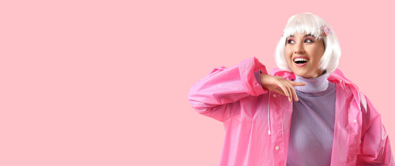 Fototapeta premium Beautiful young happy woman in white wig and raincoat on pink background