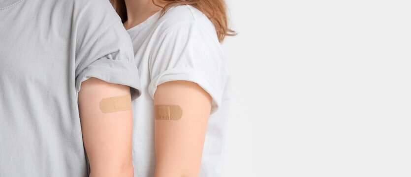 Young couple with applied medical patches on light background with space for text, closeup. Immunization concept - Powered by Adobe