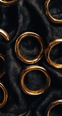 Golden rings gleam on dark, textured fabric, close-up view