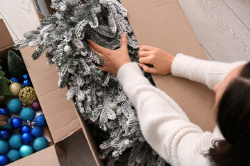 Woman putting Christmas tree in cardboard box at home, closeup