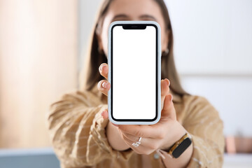 Young woman holding mobile phone with blank screen in kitchen