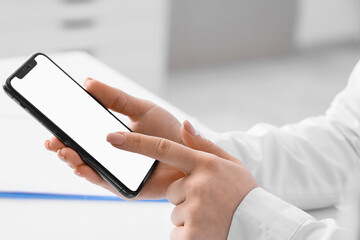 Female hands holding mobile phone with blank screen in office
