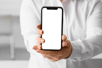 Young woman holding mobile phone with blank screen in office, closeup