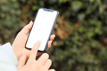 Young woman using mobile phone with blank screen in park