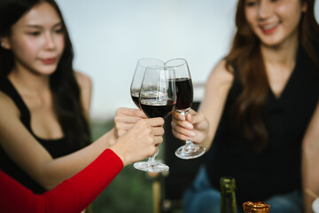 Two young women enjoying grilled food and wine together at an outdoor party, smiling and chatting in a relaxed, friendly atmosphere.