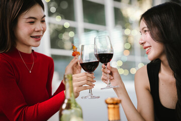 Two young women enjoying grilled food and wine together at an outdoor party, smiling and chatting in a relaxed, friendly atmosphere.