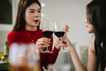Two young women enjoying grilled food and wine together at an outdoor party, smiling and chatting in a relaxed, friendly atmosphere.