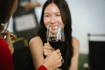 Two young women enjoying grilled food and wine together at an outdoor party, smiling and chatting in a relaxed, friendly atmosphere.