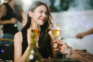 Two young women enjoying grilled food and wine together at an outdoor party, smiling and chatting in a relaxed, friendly atmosphere.