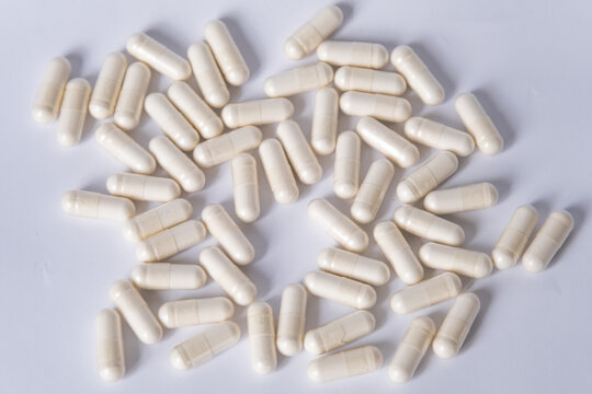 White capsules with lactobacilli or probiotics on a white background. Photographed from above.