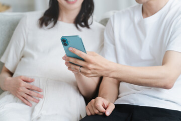 スマートフォンを操作する妊婦と夫　ライフスタイルイメージ