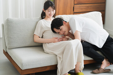 妊婦のお腹に耳を当てる夫　ライフスタイルイメージ