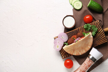 Wooden board of delicious pita with falafel and fresh vegetables on white background