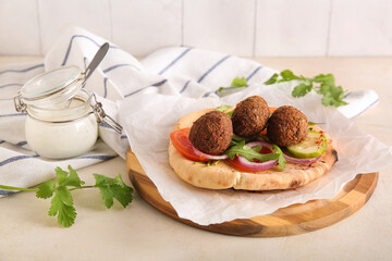 Wooden board of delicious pita with falafel and fresh vegetables on white table