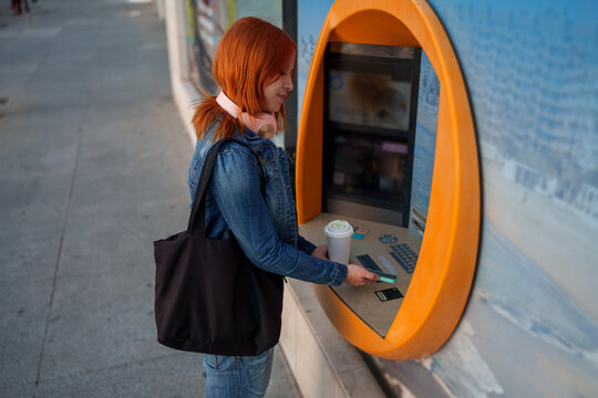 Young woman making a financial transaction using smartphone tap at an ATM. Enjoying modernity and convenience of digital banking
