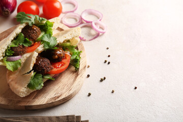 Wooden plate of delicious pitas with falafel and fresh vegetables on white background