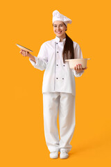 Young female chef with cooking pot on yellow background