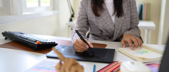 Graphic designer using digital drawing tablet while developing colorful logo concept