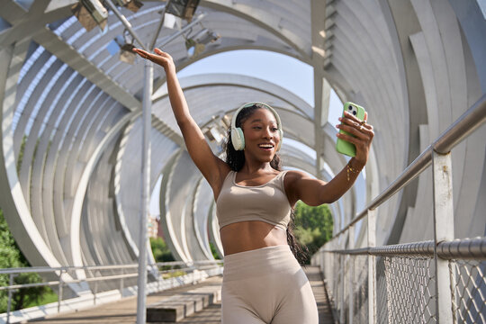 Young sporty influencer dancing while recording a video on a bridge