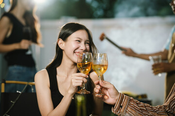 Group of friends enjoying barbecue and wine together in a cozy outdoor party, smiling and chatting in a cheerful atmosphere.