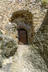 An arched passage in the wall of the fortress leading outside. A wooden door with iron hinges and a bolt. Khuluti fortress. Georgia