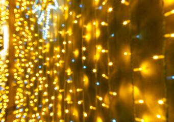 golden holiday christmas background of yellow garland with blurred backdrop, pattern for celebration new year design