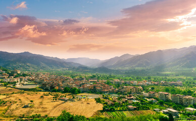beautiful evening or morning landscape of amazing small mountain town in highland walley with houses and orange roofs and nice sunset cloudy sky with mountains on background