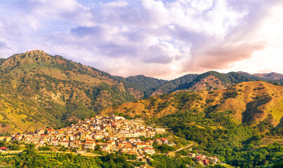 highland landscape of italian town between amazing green mountains with scenic sunset cloudy sky on background