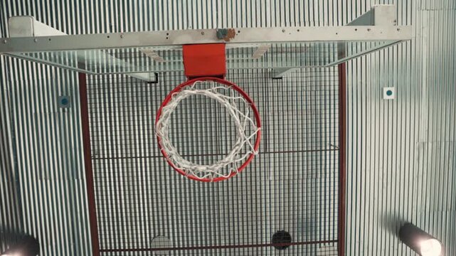 Slow motion footage of a basketball swishing through the hoop in an indoor court.