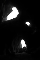 Monochrome cave interior with bright openings creating contrast and depth in the image view