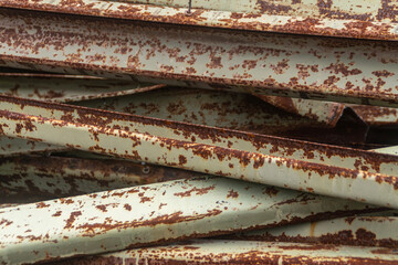 A close-up view of stacked rusty steel channels showing corrosion and texture.
