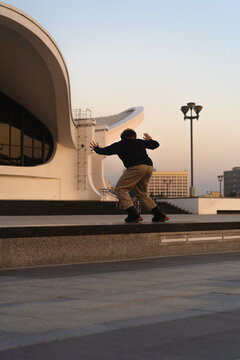 Man performing a trick on roller skates at sunset, urban environment