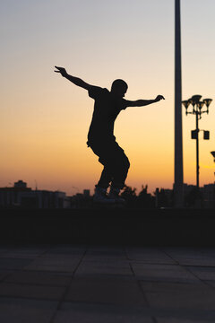 Man performing a trick on roller skates at sunset, urban environment