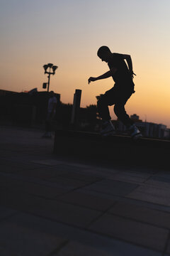 Man performing a trick on roller skates at sunset, urban environment