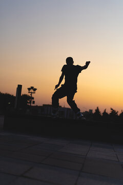 Man performing a trick on roller skates at sunset, urban environment