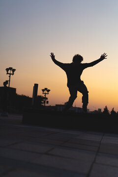 Man performing a trick on roller skates at sunset, urban environment
